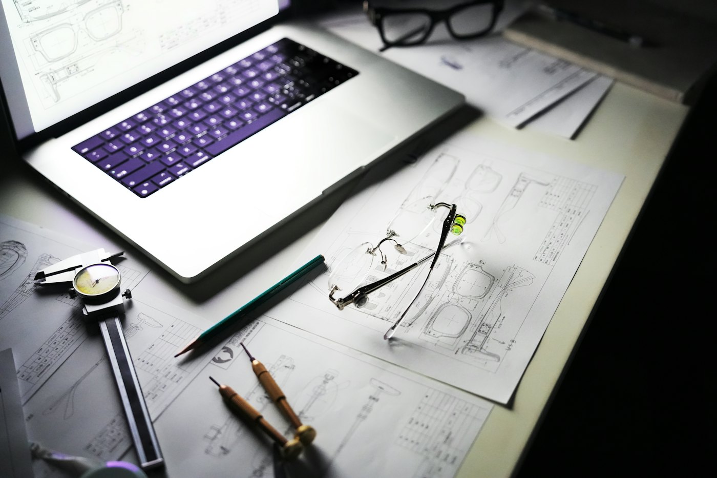 Scrivania con computer portatile, disegni di progetto e strumenti di misura